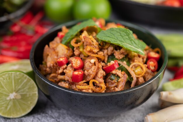 Braciole di maiale piccanti in una tazza nera composta da limoni chili e contorni