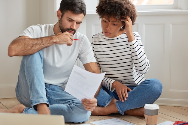 Brainstorming e concetto di collaborazione. Colleghi femminili e maschi di razza mista concentrati assegnano i costi insieme