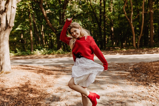 Brillante giovane donna che balla sul sole nel parco. Bella bionda sorridente felicemente fuori.