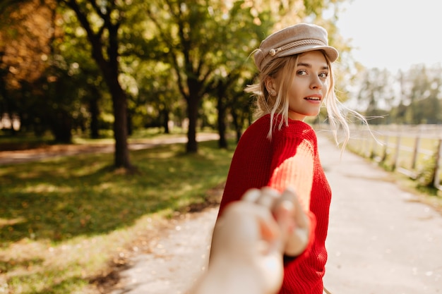 Brillante ragazza bionda che osserva affascinante seguendo una persona sul sentiero del parco.