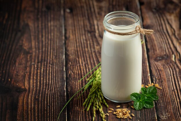 Brocca di latte di riso con pianta di riso e seme di riso messo sul pavimento di legno