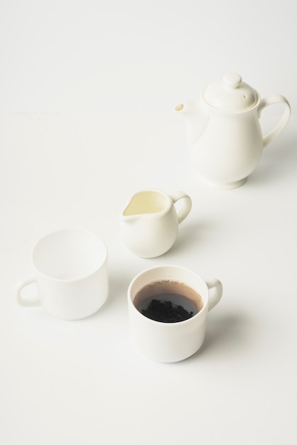 Brocca di latte; tazza di tè; tazza di ceramica e teiera su sfondo bianco