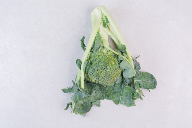 Broccoli biologici con foglie sulla superficie bianca