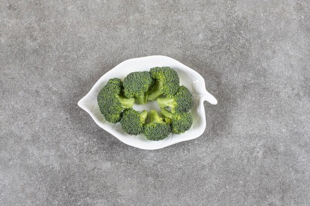 Broccoli maturi su un piatto, sul tavolo di marmo.