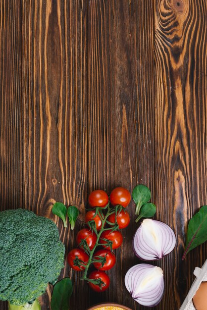 Broccoli; pomodori ciliegini; cipolla e spinaci tagliati a metà sulla scrivania