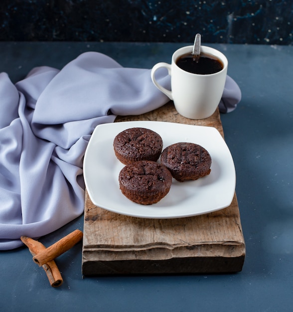 Brownies al cioccolato, bastoncini di cannella e una tazza di caffè.