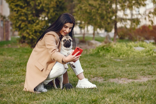 Bruna in un cappotto marrone cammina con pug