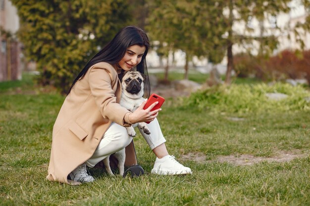 Bruna in un cappotto marrone cammina con pug