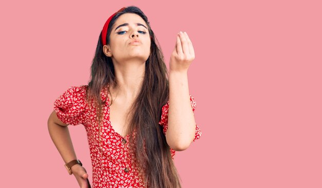 Bruna ragazza adolescente che indossa abiti estivi facendo gesto italiano con la mano e le dita espressione fiduciosa