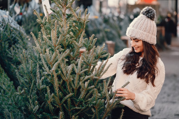 Brunetta carina in un maglione bianco con albero di Natale