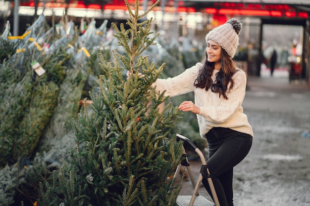 Brunetta carina in un maglione bianco con albero di Natale