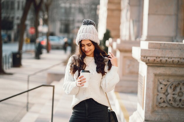 Brunetta carina in un maglione bianco in una città