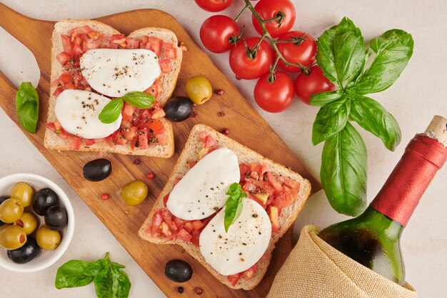 Bruschetta con pomodori, mozzarella e basilico su un tagliere. Antipasto o spuntino tradizionale italiano, antipasto. Bruschetta con insalata caprese. Vista dall'alto con copia spazio. Lay piatto.