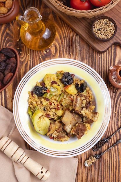 Bulgur con la vista superiore di frutti asciutti delle spezie del peperone dolce delle prugne dello zucchini della carne