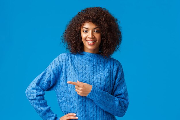 Buon affare proprio sopra l'angolo. Fiduciosa e piacevole donna afroamericana dall'aspetto amichevole con taglio di capelli afro, chiedendo il check-out, visita la pagina del negozio, puntando il dito a sinistra e sorridendo alla telecamera.