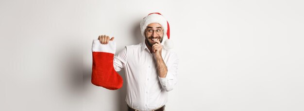 Buon natale vacanze concetto uomo adulto che sembra felice e curioso al calzino di natale ricevere regali di usura