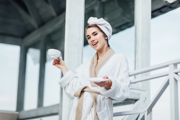 buongiorno. Concetto di bellezza, ragazza sorridente passa il fine settimana e tiene in mano una tazza di tè, bella mattinata.