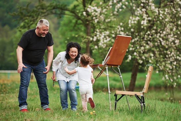 Buongiorno. Nonna e nonno si divertono all'aperto con la nipote. Concezione della pittura