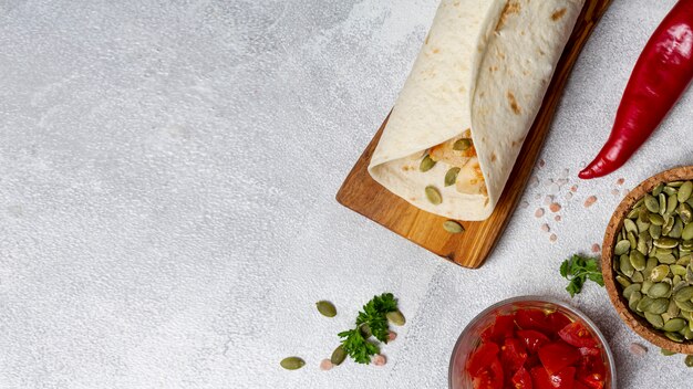 Burrito vicino a peperoni, semi di cardamomo e pomodori a fette