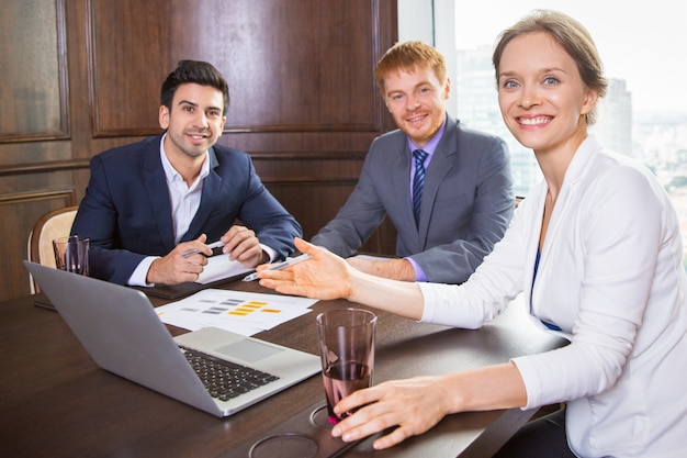 Business donna seduta con due uomini in tuta sorridente