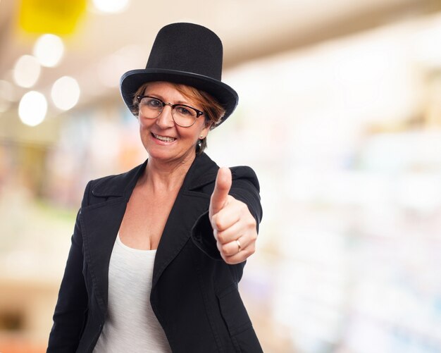 Business donna sorridente con un cappello a cilindro e un pollice in alto