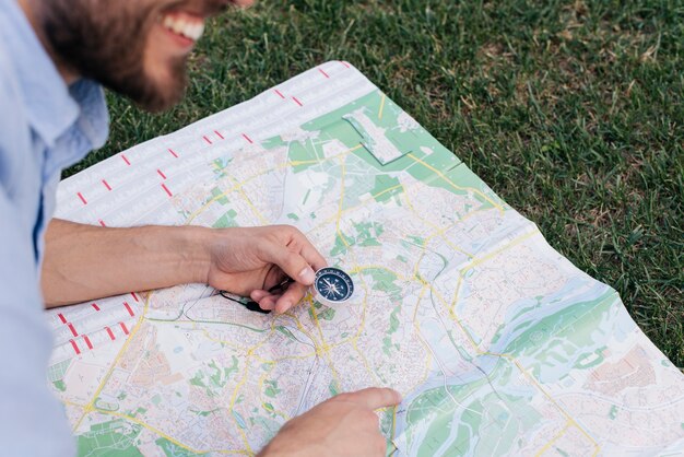 Bussola sorridente della tenuta dell'uomo e indicare alla mappa su erba