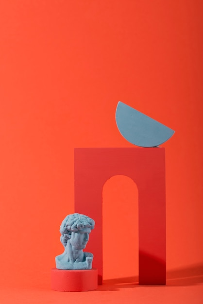 Busto in gesso su fondo corallo con forme geometriche