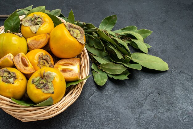 Cachi dolci freschi di vista superiore all'interno del canestro sui frutti pastosi del pavimento scuro maturi