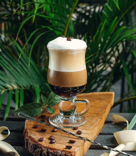 caffè a strati con panna e chicchi di caffè sul bordo di legno rustico