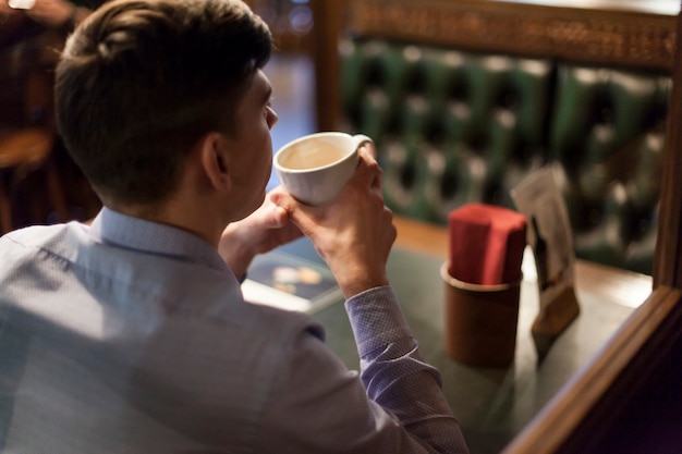 Caffè bevente dell&#39;uomo di vista posteriore in ristorante