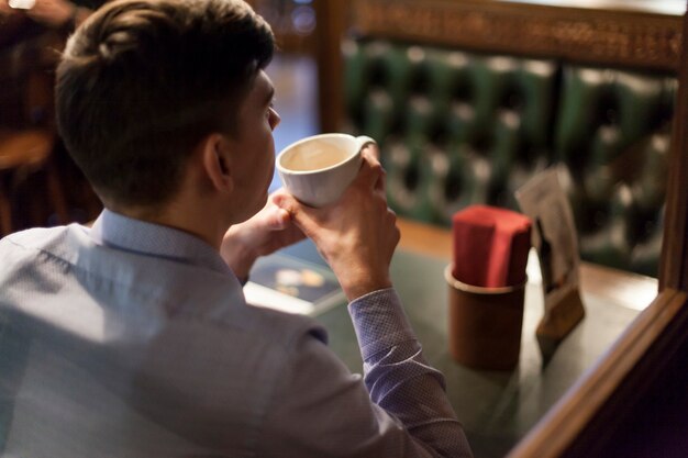 Caffè bevente dell&#39;uomo di vista posteriore in ristorante