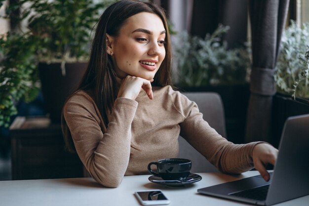 Caffè bevente della donna di affari e lavorare al computer portatile in un caffè