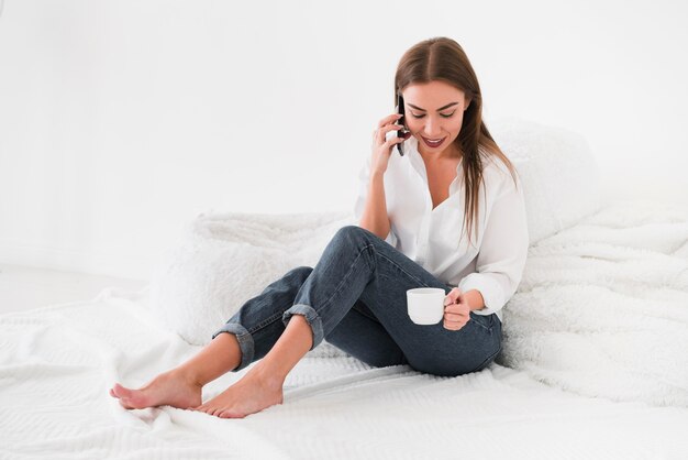 Caffè bevente della donna di vista lunga a letto