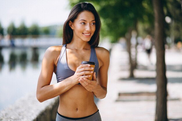 Caffè bevente della donna sportiva in parco