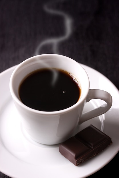 Caffè caldo con un pezzo di cioccolato