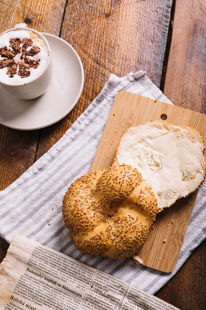 Caffè cappuccino e fetta di pane con formaggio sul tagliere sopra il tavolo