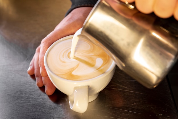 Caffè di versamento di barista del primo piano nella tazza