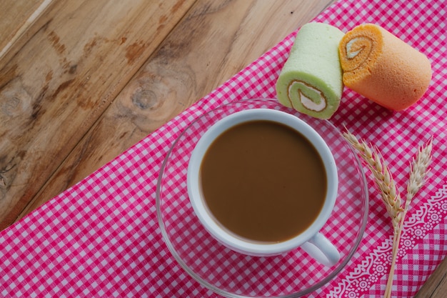 Caffè e pane disposti su un panno fantasia rosa su un pavimento di legno marrone.