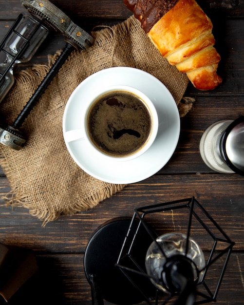 Caffè espresso caldo con cornetto sul tavolo