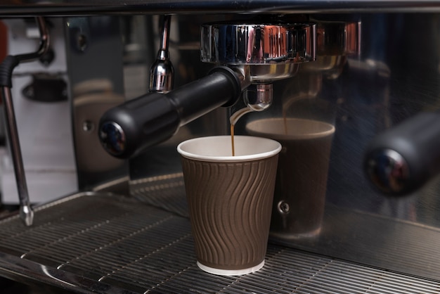 Caffè espresso del primo piano che versa nella tazza di caffè