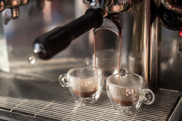 Caffè espresso del primo piano che versa nelle tazze