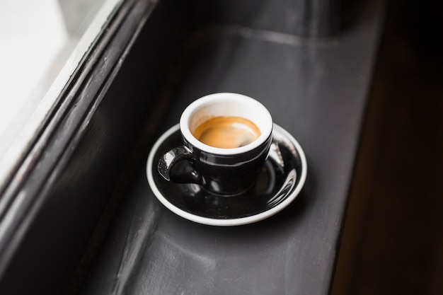 Caffè rimanente in tazza nera sul davanzale della finestra