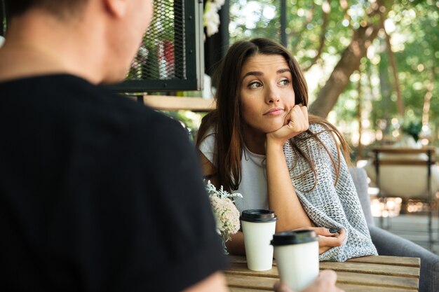 Caffè stanco di seduta e bevente della donna annoiata