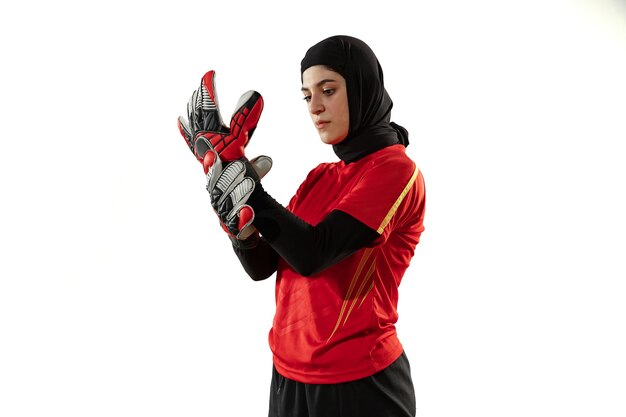 Calcio femminile arabo o giocatore di football americano, portiere su sfondo bianco studio. Giovane donna che prepara per il gioco, la formazione, la protezione degli obiettivi per la squadra. Concetto di sport, hobby, stile di vita sano.