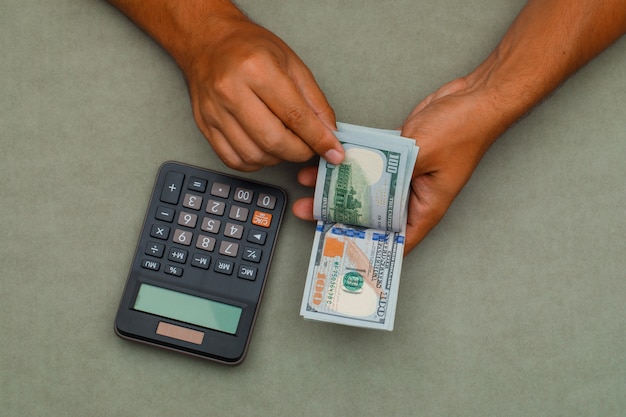 calcolatrice sul tavolo grigio verde e uomo contando le banconote da un dollaro.