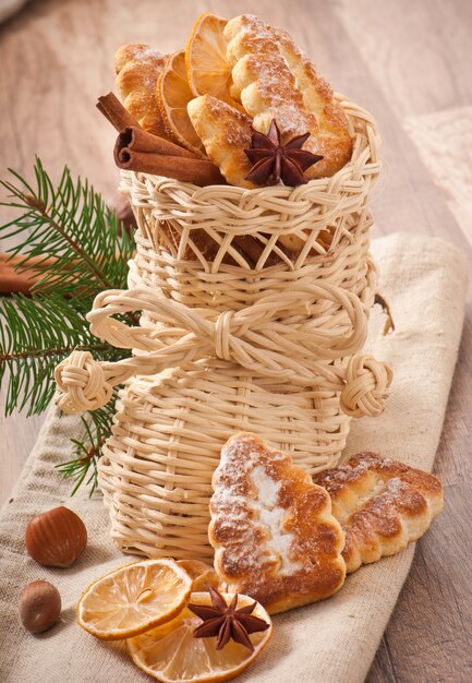 Calza natalizia in vimini riempita con biscotti, bastoncini di cannella, limone candito e anice stellato