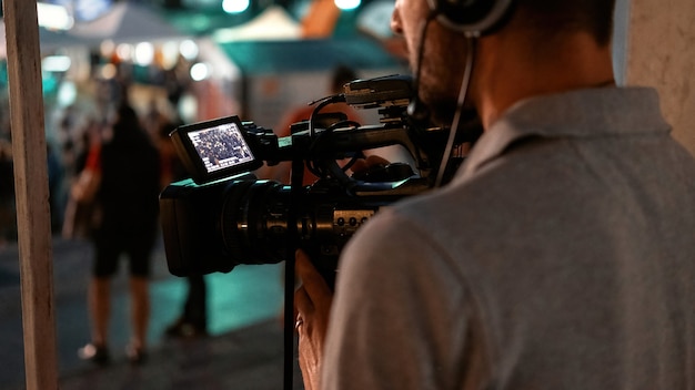 Cameraman professionista che registra persone che guardano il calcio in un luogo pubblico di notte