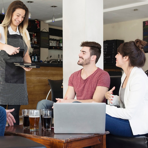 Cameriera che dà menu ai clienti nel bar