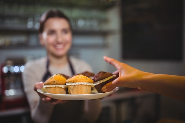 Cameriera che serve un piatto di Cupcake al cliente