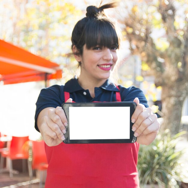 Cameriera femminile che mostra telefono cellulare con lo schermo bianco in bianco a all&#39;aperto